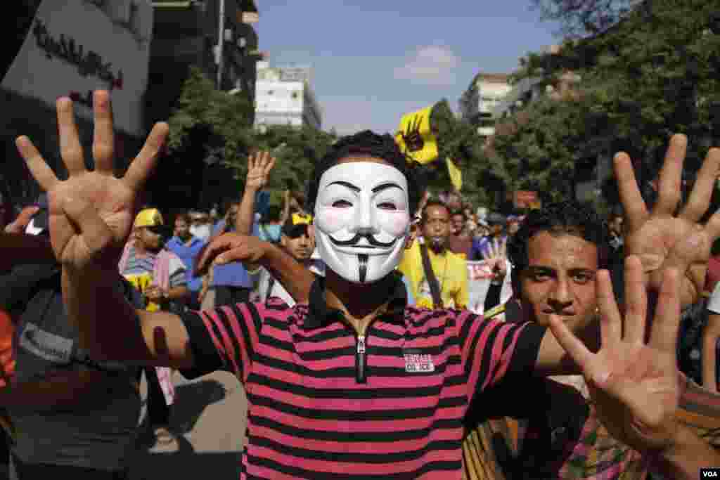 A masked protester holds up four fingers as he marches in Maadi, southern Cairo, Sept. 20, 2013. (Hamada Elrasam for VOA)