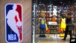 FILE - A man walks past statues of NBA players Stephen Curry of the Golden State Warriors, left, and Lebron James of the Los Angeles Lakers holding Chinese flags in the entrance of an NBA merchandise store in Beijing, Oct. 8, 2019.