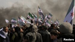 Warga mengibarkan bendera-bendera oposisi menentang kesepakatan patroli bersaa Rusia-Turki di jalan raya M4, Provinsi Idlib, Suriah, 15 Maret 2020. (Foto: Reuters)