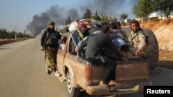 FILE - Rebel fighters ride a pickup truck with civilians fleeing conflict in Dahiyet al-Assad, west Aleppo city, Syria, Oct. 30, 2016. A new cease-fire allows civilians and rebels to leave the embattled city. 