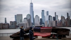 People wear face mask as they walk near a 9-11 memorial during the coronavirus disease (COVID-19) pandemic, while the One World Trade Center and New York skyline are seen from Exchange Place, in New Jersey