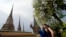 Western tourists snap a souvenir photo at a Wat Pho temple in Bangkok, Thailand.