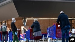 People queue at a supermarket, March 21, 2020, in Turin, Italy. Italian Premier Giuseppe Conte tightened the lockdown to fight the spread of the coronavirus, shutting down all production facilities except those that are necessary.