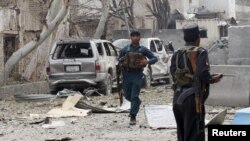 An Afghan policeman runs during the gunfire in front of the Indian consulate in Jalalabad, Afghanistan, March 2, 2016.