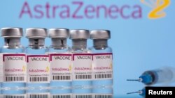 Jajaran ampul bertuliskan "Vaksin COVID-19 Astra Zeneca" dan sebuah suntikan di depan logo AstraZeneca, Minggu, 14 Maret 2021.