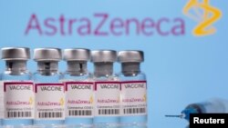 Vials labelled "Astra Zeneca COVID-19 Coronavirus Vaccine" and a syringe are seen in front of a displayed AstraZeneca logo, in this illustration photo taken March 14, 2021.