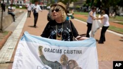 A government supporter holds an Argentine flag that reads in Spanish "Thanks Cristina" featuring an image of late President Nestor Kirchner and his wife, current President Cristina Fernandez in Buenos Aires, Argentina, on Dec. 9, 2015. 