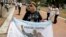 A government supporter holds an Argentine flag that reads in Spanish "Thanks Cristina" featuring an image of late President Nestor Kirchner and his wife, current President Cristina Fernandez in Buenos Aires, Argentina, on Dec. 9, 2015. 