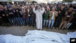 Los palestinos rezan sobre los cuerpos de las víctimas de un ataque israelí contra una casa el sábado por la noche antes del funeral frente al Hospital de los Mártires de Al-Aqsa en Deir al-Balah el domingo 22 de diciembre de 2024. AP