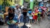 Locals wearing protective masks carry plates while queueing for food distributed for free amid the spread of coronavirus disease (COVID-19) in Bandung, West Java province, Indonesia.