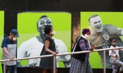 People wearing face masks queue at a South African Social Security Agency (SASSA) to collect their government grant in Cape Town, South Africa, May 11, 2020.