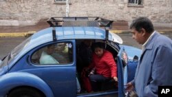 El taxista Rafael Ortega ayuda a los pasajeros a entrar en un Beetle de Volkswagen en el vecindario de Cuautepec en Ciudad de México, el 21 de junio de 2024