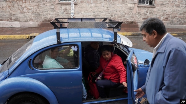 El taxista Rafael Ortega ayuda a los pasajeros a entrar en un Beetle de Volkswagen en el vecindario de Cuautepec en Ciudad de México, el 21 de junio de 2024