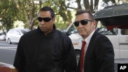 AC/DC drummer Phil Rudd, right, who pleaded guilty to a charge of threatening to kill a man who used to work for him, arrives at a court in Tauranga, New Zealand, April 21, 2015. 