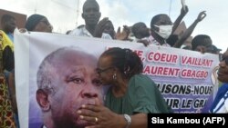 Un partisan de l'ancien président ivoirien Laurent Gbagbo, président du Front populaire ivoirien (FPI), à côté d'une banderole à son effigie, à Abidjan le 31 août 2020, lors de la remise du dossier de candidature de M. Gbagbo à la CEI. (Photo par SIA KAMBOU / AFP)