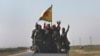 FILE - U.S.-backed Syrian Democratic Forces fighters stand on their pickup as the flash victory signs after battling the Islamic State militants, northeast Syria, July 26, 2017.