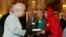 Malala Yousafzai, derecha, entrega una copia de su libro a la reina Elizabeth de Inglaterra durante una recepción en honor a la juventud celebrada en palacio.