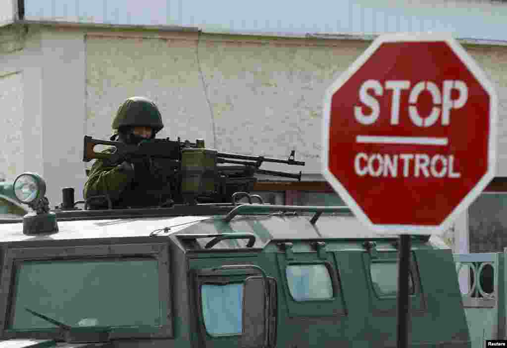 An armed man, believed to be a Russian serviceman, stands guard outside an Ukrainian military base in Perevalnoye, near the Crimean city of Simferopol, March 13, 2014. 