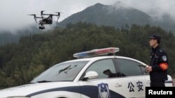 FILE - A police officer of the Forest Public Security Bureau operates a drone in Lishui, Zhejiang province, China, April 4, 2018. Police in China used drones to track down a fugitive who had escaped from a prison camp 17 years ago.