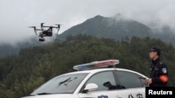 FILE - A police officer of the Forest Public Security Bureau operates a drone in Lishui, Zhejiang province, China, April 4, 2018. Police in China used drones to track down a fugitive who had escaped from a prison camp 17 years ago.