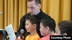 Children awaiting their turn to read while poet and educator Dave Johnson looks on.