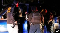 In this Oct. 22, 2018, photo U.S. Immigration and Customs Enforcement agents surround and detain a person during a raid in Richmond, Va. ICE's enforcement and removal operations, like the five-person field office team outside Richmond, hunt people…