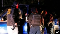 FILE - U.S. Immigration and Customs Enforcement agents surround and detain a person during a raid in Richmond, Virginia, Oct. 22, 2018.