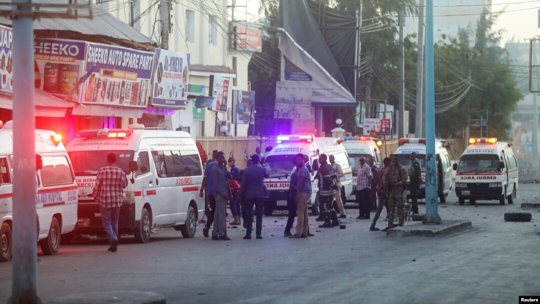 Bezbednosne snage Somalije obezbeđuju mesto eksplozije automobila bombe, dok vozila hitne pomoći čekaju kako bi se ukazala ponoć povređenima u oblasti poznatoj kao Četvrti kilometar u Mogadišu, Somalija, 31. januara 2021. (RojtersS/Feisal Omar)