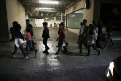 FILE - Migrants who have been bused by Mexican authorities from Nuevo Laredo to Monterrey, walk on a street in Monterrey, Mexico, July 18, 2019.