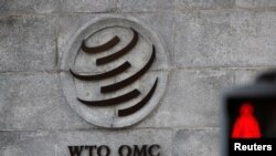 Logo di luar markas Organisasi Perdagangan Dunia (WTO) di sebelah lampu merah di Jenewa, Swiss, 2 Oktober 2018. (Foto: Reuters/Denis Balibouse)