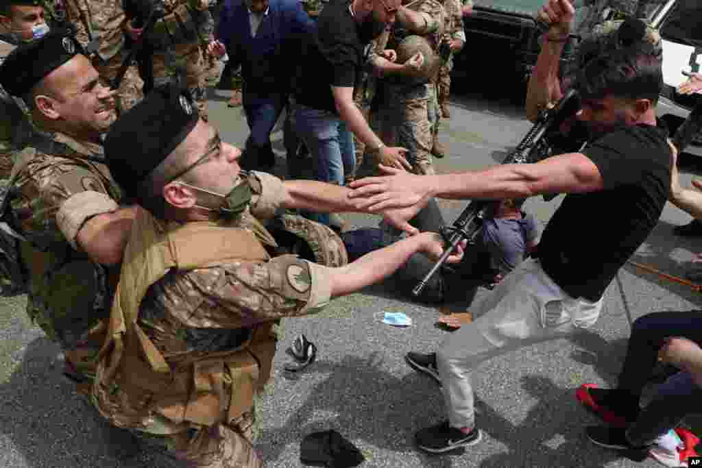 An opponent of Judge Ghada Aoun grabs the weapon of a soldier, after he was hit, during a sit-in outside the Justice Palace in Beirut, Lebanon.