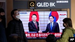 Orang-orang melewati layar TV yang memperlihatkan Presiden Korea Selatan Yoon Suk Yeol, kiri, bertemu dengan Perdana Menteri Jepang Fumio Kishida di Jepang, selama program berita di Stasiun Kereta Api Seoul di Seoul, Korea Selatan, Kamis, 16 Maret 2023. (Foto: AP)