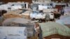 FILE - Syrian refugees stand outside their tents at a Syrian refugee camp in the town of Hosh Hareem, in the Bekaa valley, east Lebanon, Oct. 28, 2015. 