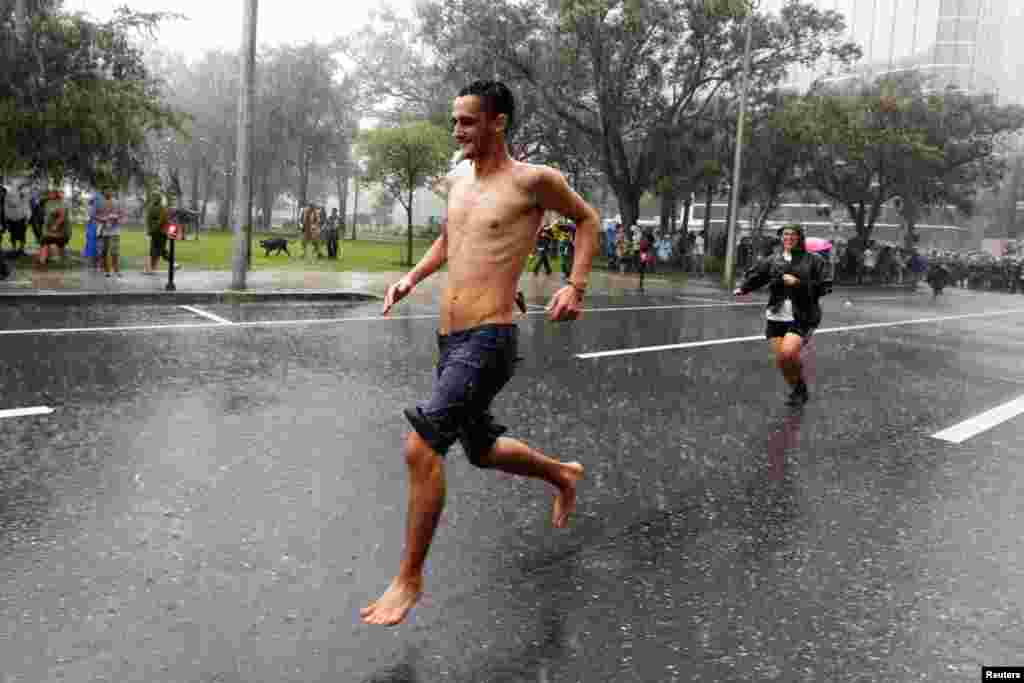 A sudden, heavy rainstorm surprises protesters outside near the convention center.