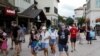 Para pengunjung pusat belanja Disney Springs di Lake Buena Vista, Florida, mengenakan masker wajah saat dibukanya kembali secara bertahap Walt Disney World setelah beberapa bulan tutup akibat pandemi Covid-19) AS 11 Juli 2020. REUTERS / Octavio Jones
