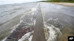 Waters from the Gulf of Mexico poor onto a local road, Monday, Sept. 14, 2020, in Waveland, Miss.