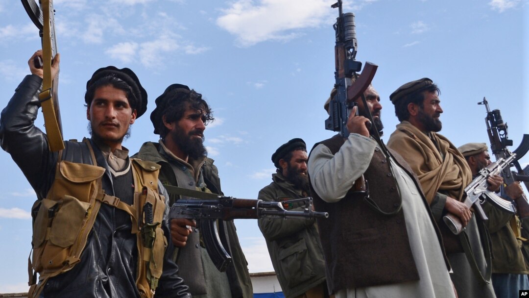 Afghan militia men raise their weapons as they stand guard in the Achin district of Nangarhar province east of Kabul, Afghanistan, Dec. 27, 2015.