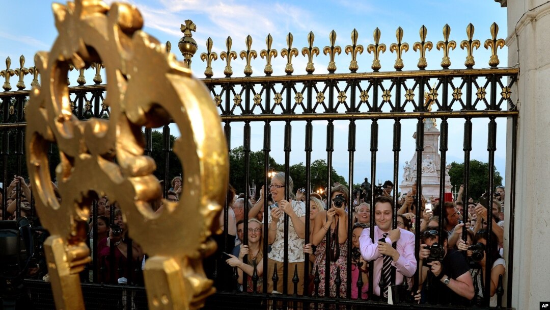 Warga berkerumun di depan Istana Buckingham untuk membaca pengumuman tentang kelahiran Pangeran Kerajaan Inggris, putra pertama Pangeran William dan istrinya Kate, pada jam 4: 24 sore waktu setempat (22/7).