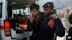 Un guardia de seguridad ayuda a un estudiante herido luego del ataque a la escuela militar en Peshawar, Pakistán.