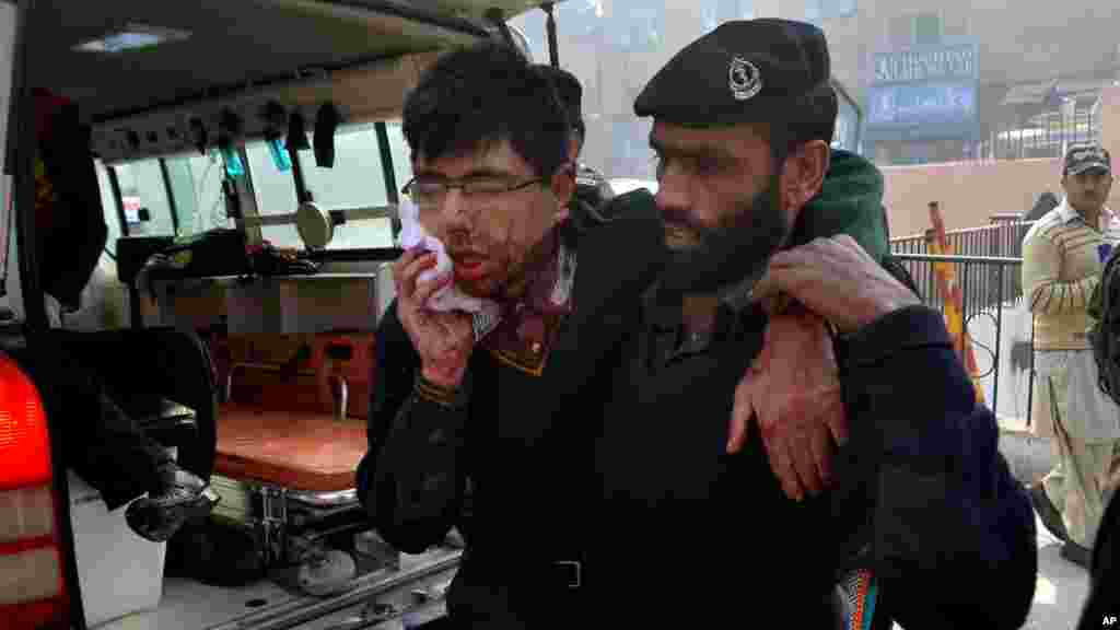 A hospital security guard helps a student injured in the shootout at a school under attack by Taliban gunmen in Peshawar, Pakistan,Tuesday, Dec. 16, 2014.