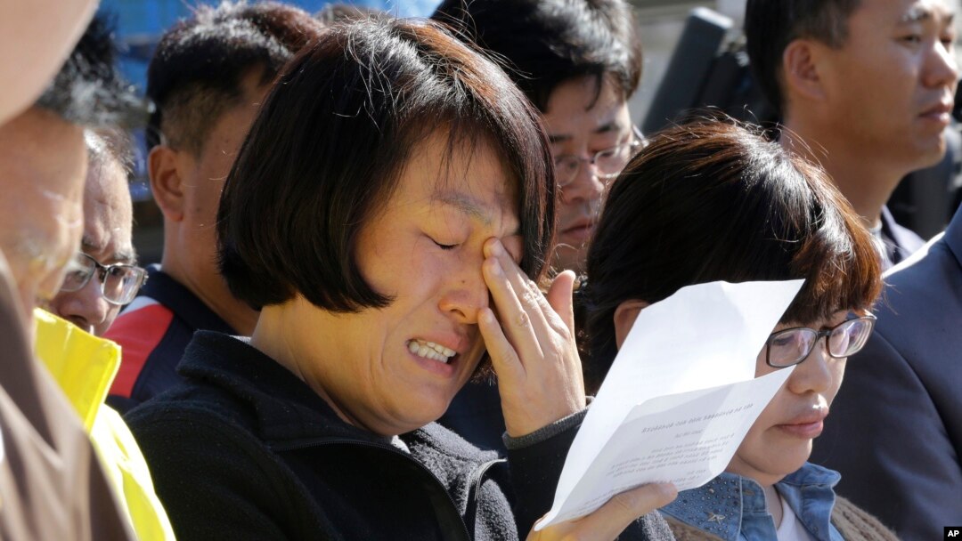 An unidentified family member of passengers aboard the sunken ferry Sewol caries as she demands maximum punishment to be sentenced on the crew members of the ferry during their trial at Gwangju District Court in Gwangju, South Korea, Oct. 27, 2014. 