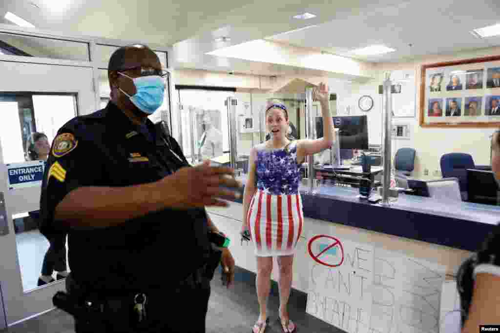 A parent and a member of the Community Patriots group confronts a police officer while she protests wearing masks in schools, at the Pinellas County Schools Administration Building in Largo, Florida, Aug. 9, 2021.