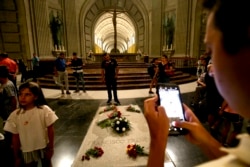 FILE - People stand around the tomb of former Spanish dictator Francisco Franco inside the basilica at the the Valley of the Fallen monument near El Escorial, Aug. 24, 2018.