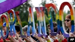 Members of Capital City Pride and others from the LGBT community hold up letters spelling out "Orlando" to honor of the recent shooting at a gay nightclub days earlier before the raising of a rainbow flag in front of the Washington state Capitol, June 15, 2016.