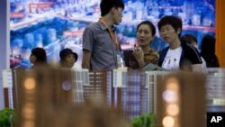 FILE - People view housing models on display during the China Property and Investment Show in Beijing, Sept. 21, 2012. 