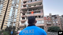 Un policía libanés observa los apartamentos dañados que fueron alcanzados por un ataque israelí la madrugada del lunes 30 de septiembre de 2024. (Foto AP/Hussein Malla)