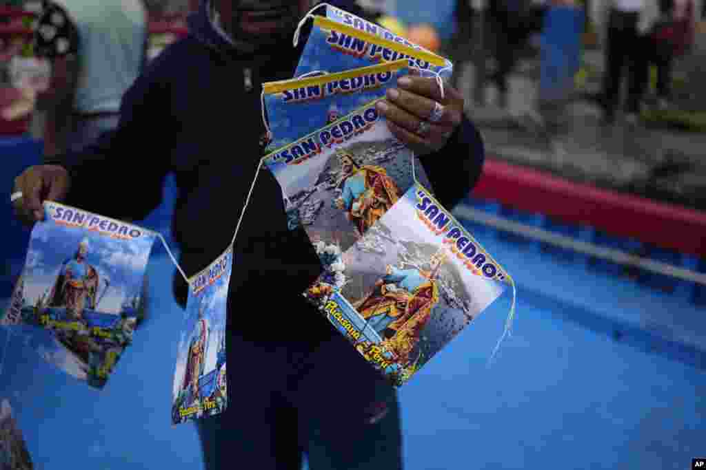 Un pescador muestra estampas de San Pedro, santo patrón católico de los pescadores, durante la procesión de su celebración en la ciudad costera de Pucusana, Perú, el jueves 29 de junio de 2023.