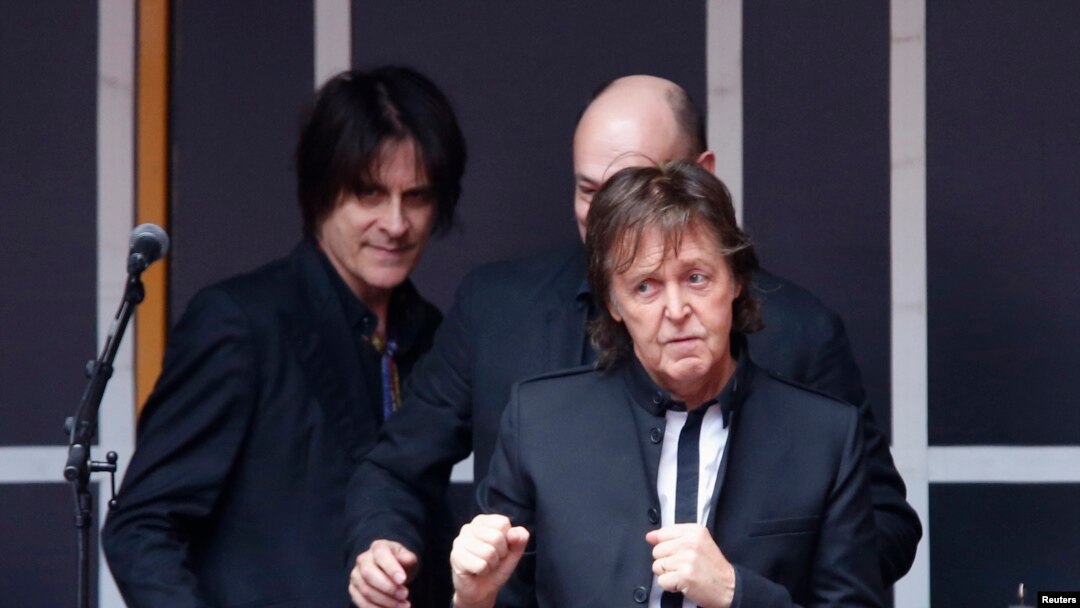 Singer Paul McCartney gestures to audience after playing a surprise mini-concert in New York's Times Square, Oct. 10, 2013.