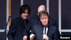 Singer Paul McCartney gestures to audience after playing a surprise mini-concert in New York's Times Square, Oct. 10, 2013.