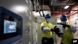 The temperature on a freezer reads -69&deg;C as workers move boxes containing the Pfizer-BioNTech COVID-19 vaccines to be shipped at the Pfizer Global Supply Kalamazoo manufacturing plant in Portage, Michigan.
